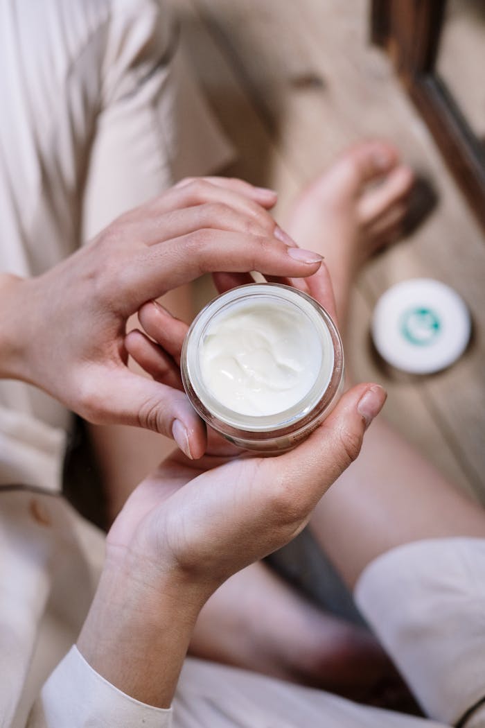 Close-up of womans hands applying skincare cream during morning routine indoors.